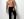 Shirtless male model in black pants and sunglasses poses confidently in a studio setting.